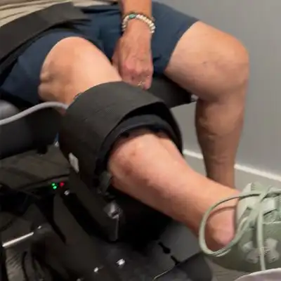 Patient receiving knee decompression therapy with a support brace and treatment device applied to the knee during a rehabilitation session.